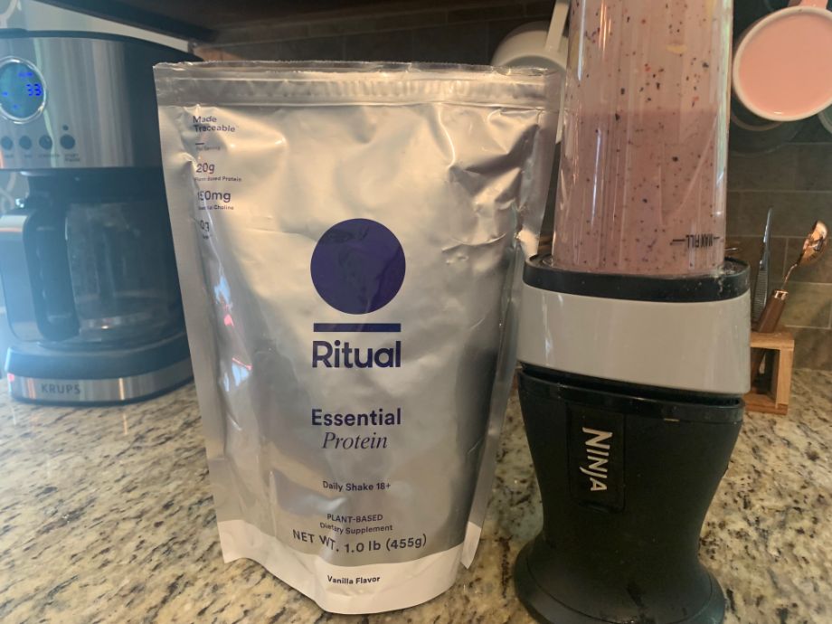 ritual essential shake 18+ in blender next to bag of one of the top protein powder
